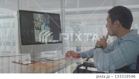 Wheelchair user wearing blue shirt viewing monitor screen at office desk, with smartphone Wheelchair user wearing blue shirt viewing monitor screen at office desk, with smartphone 133319546
