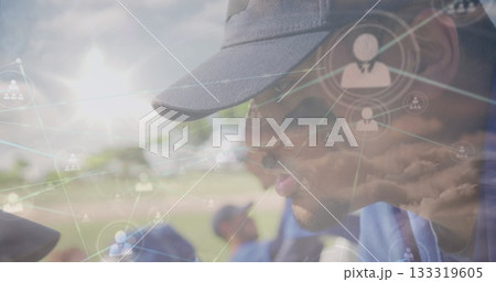 Leaning coach guiding kneeling team wearing blue jerseys on field with network overlays, copy space 133319605