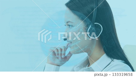 Contemplating Asian agent wearing white shirt and headset at office desk, viewing holographic globe 133319658