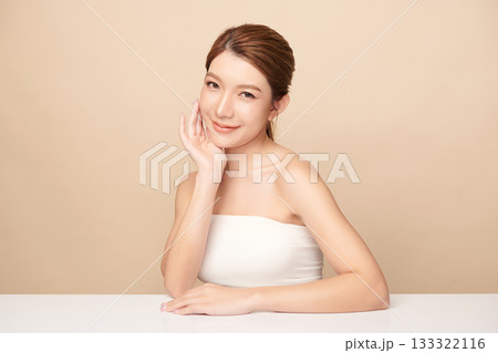 A beautiful young Asian woman with clean, fresh skin against a beige background. Skincare, facial treatment, cosmetology, beauty, and spa. An elegant portrait of an Asian woman. 133322116