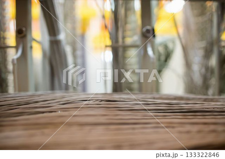 Woven rattan tabletop sitting in flat design lounge backdrop, featuring metal rails and warm lights Woven rattan tabletop sitting in flat design lounge backdrop, featuring metal rails and warm lights 133322846