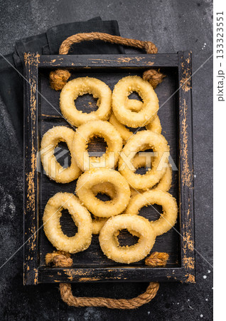 Raw squid rings with breading, uncooked calamari snack. black background. top view Raw squid rings with breading, uncooked calamari snack. black background. top view 133323551