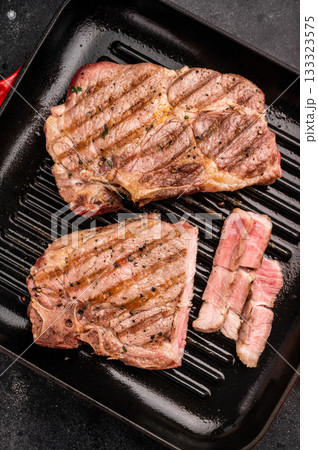 Fried on grill skillet pork tender steak, neck meat. black background. top view Fried on grill skillet pork tender steak, neck meat. black background. top view 133323575