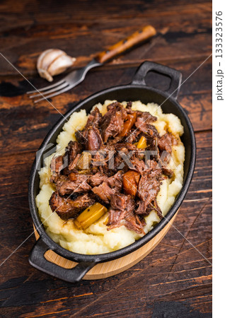 Braised Beef Cheek, Slow cooked meat with smashed potatoes in a skillet. wooden background. top view 133323576