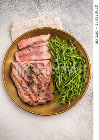 Roasted BBQ pork neck meat steak on plate with salad. grey background. top view 133323610