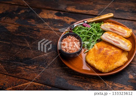 Chicken Fried cordon bleu cutlet on plate with salad. wooden background. top view Chicken Fried cordon bleu cutlet on plate with salad. wooden background. top view 133323612