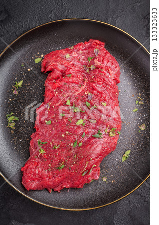 Marinated Flank or Flap steak, raw beef meat with thyme and spices on plate. black background. top view Marinated Flank or Flap steak, raw beef meat with thyme and spices on plate. black background. top view 133323633