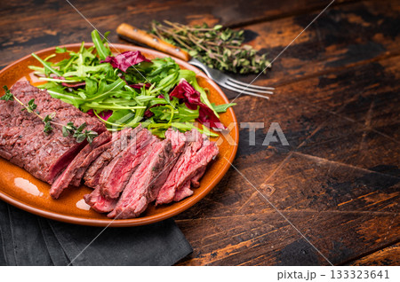 Grilled Skirt machete beef steak, roasted sliced meat on plate with salad. wooden background. top view 133323641