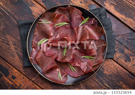Spanish tapa Cecina meat slices, beef jamon on plate with herbs. wooden background. top view Spanish tapa Cecina meat slices, beef jamon on plate with herbs. wooden background. top view 133323654