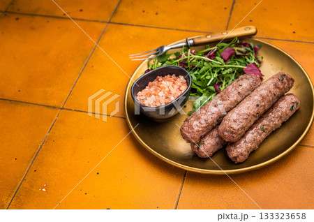 Grilled kofta or lula kebabs from mince lamb and beef meat on a plate with salad. brown background. top view Grilled kofta or lula kebabs from mince lamb and beef meat on a plate with salad. brown background. top view 133323658