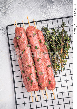 Raw kofta or lula kebabs skewers from mince lamb and beef meat on Skewer. grey background. top view Raw kofta or lula kebabs skewers from mince lamb and beef meat on Skewer. grey background. top view 133323754