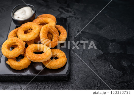 Deep fried squid rings with breading, calamari fastfood snack. black background. top view 133323755