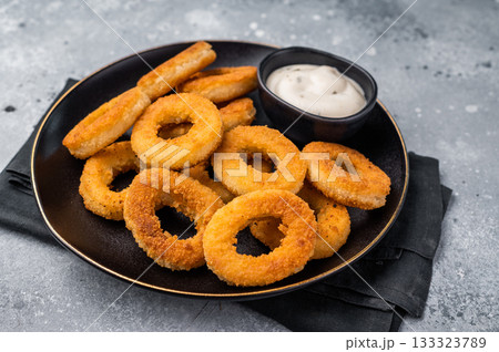 Fried squid rings, calamari seafood snack in a plate with deep. grey background. top view Fried squid rings, calamari seafood snack in a plate with deep. grey background. top view 133323789