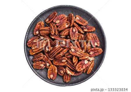 Shelled pecan halves spread on a dark plate over a bright white background creating a clean contrasting ingredient scene ideal for culinary themes Shelled pecan halves spread on a dark plate over a bright white background creating a clean contrasting ingredient scene ideal for culinary themes 133323834