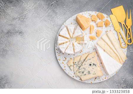 Variety of sliced Brie creamy Camembert aged Parmesan and Roquefort photographed on terrazzo with a subtle gray textured background. 133323858