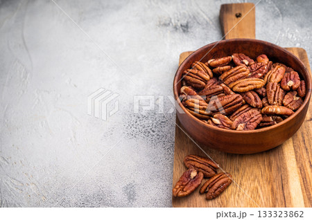 Fresh pecan nuts arranged in a rustic wooden bowl over a plain white backdrop giving a clean organic look suitable for food ingredient and nutrition content Fresh pecan nuts arranged in a rustic wooden bowl over a plain white backdrop giving a clean organic look suitable for food ingredient and nutrition content 133323862