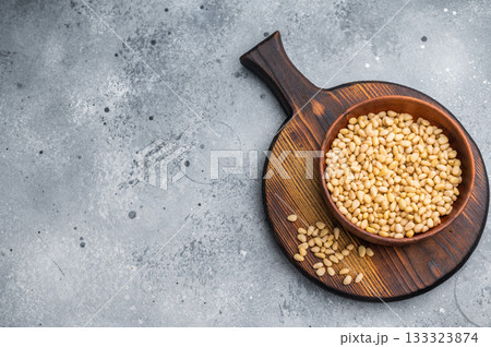 Close view of raw pine nuts in a rustic wooden bowl on a bright white backdrop giving a clean organic feel suitable for culinary and healthy food themes Close view of raw pine nuts in a rustic wooden bowl on a bright white backdrop giving a clean organic feel suitable for culinary and healthy food themes 133323874