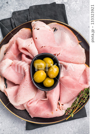 Meat appetizer with Sliced Prosciutto Cotto ham and green olives. grey background. top view 133323921