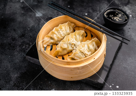 Steamed Japanese Gyoza Dumplings with pork meat and vegetables in bamboo steamer. black background. top view 133323935