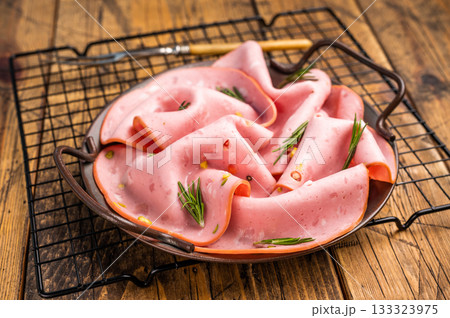 Mortadella sausage slices with pistachios for sandwiches in steel tray. wooden background. top view 133323975