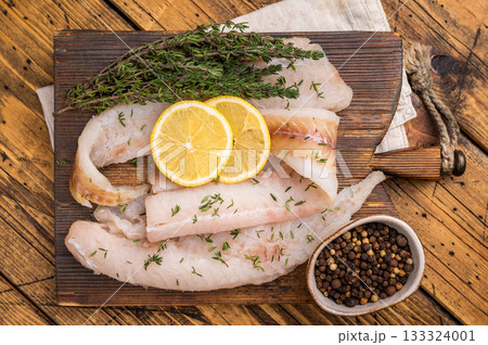 Haddock sea fish fillets, raw whitefish on a wooden board ready for cooking. wooden background. top view Haddock sea fish fillets, raw whitefish on a wooden board ready for cooking. wooden background. top view 133324001