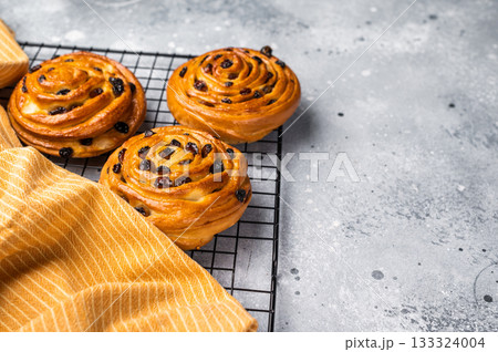 Baked Danish pastry, raisin bun on steel rack. grey background. top view 133324004