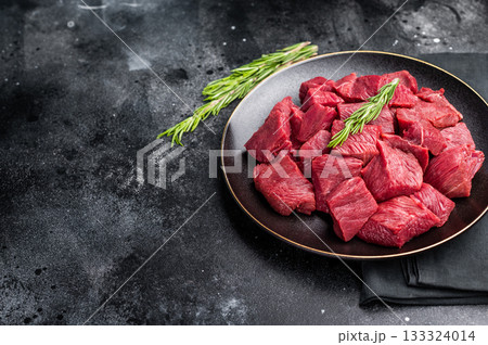 Diced Raw Boar meat, fresh Game Meat in a plate. black background. top view Diced Raw Boar meat, fresh Game Meat in a plate. black background. top view 133324014