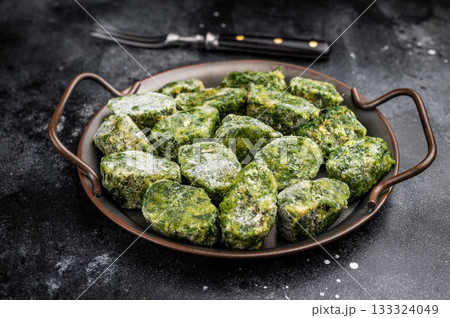 Overhead view of frozen spinach blocks in a rustic metal tray with a vintage fork. Dark, textured background with copy space. Overhead view of frozen spinach blocks in a rustic metal tray with a vintage fork. Dark, textured background with copy space. 133324049