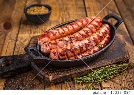 Juicy, smoky fried sausages on a wooden board with herbs and fork. High-quality image for restaurant menus or food blog headers. Juicy, smoky fried sausages on a wooden board with herbs and fork. High-quality image for restaurant menus or food blog headers. 133324054