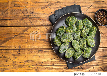 Raw, nutritious frozen spinach blocks on a dark plate, ready for thawing and cooking. Traditional rustic food photography. Raw, nutritious frozen spinach blocks on a dark plate, ready for thawing and cooking. Traditional rustic food photography. 133324065