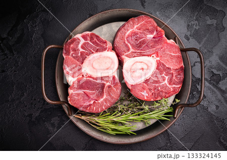 Freshly cross cut shank osso buco, ossobuco meat featuring succulent meat and bone marrow, waiting to elevate your cooking experience. black background. top view 133324145