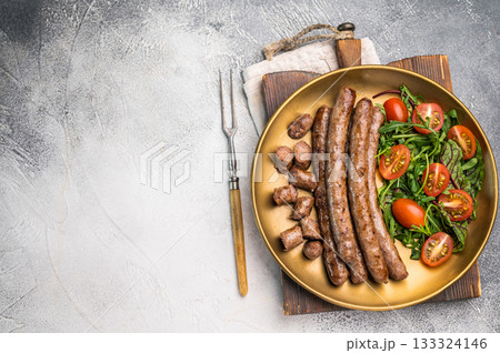 Close up of perfectly charred grilled sausage with salad, ideal for adding flavor to your favorite dishes or sandwiches. white background. top view 133324146