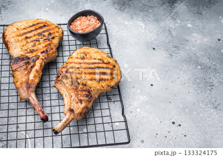 Juicy grilled pork Tomahawk chop, perfectly seared and bursting with flavor, ideal for a hearty feast. grey background. top view Juicy grilled pork Tomahawk chop, perfectly seared and bursting with flavor, ideal for a hearty feast. grey background. top view 133324175