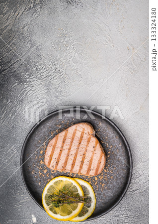 Deliciously charred grilled tuna steak, served with fresh herbs, a healthy and flavorful choice for any meal. white background. top view Deliciously charred grilled tuna steak, served with fresh herbs, a healthy and flavorful choice for any meal. white background. top view 133324180