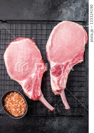 Fresh pork Chop Tomahawk steak, showcasing its impressive bone and marbled meat, perfect for grilling or roasting. black background. top view 133324190