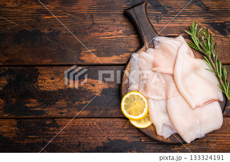 Freshly caught raw squid with glistening skin, perfect for grilling or frying to create mouthwatering dishes. wooden background. top view 133324191