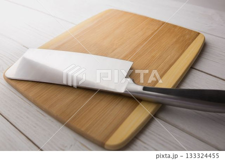 Knife and chopping board on wooden floor 133324455