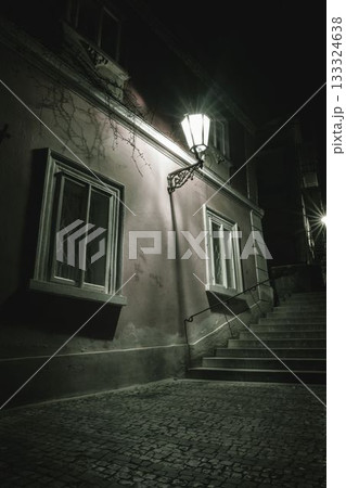 Lantern-lit facade with windows is being shown in flat night design, featuring cobblestone pavement 133324638
