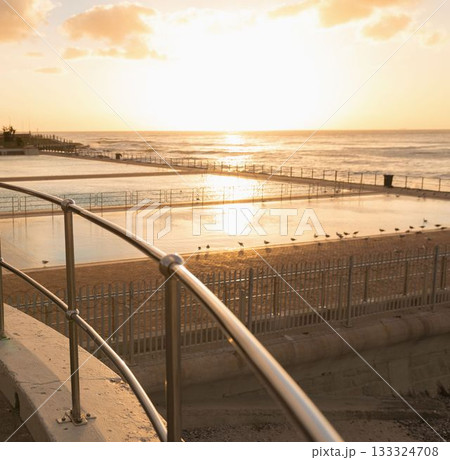 Flat design showing stainless steel handrail running over tidal pool with seagulls, pier at sunset 133324708
