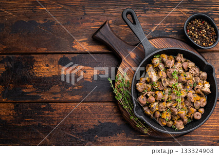 Tasty chicken offal stew in cast iron pan on dark wooden surface great for restaurant advertising or food blogs. 133324908