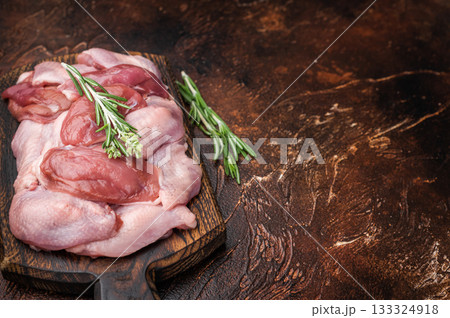 Butcher cut: Uncooked quail fillets and fresh rosemary on a dark wooden board. High-protein healthy food. 133324918