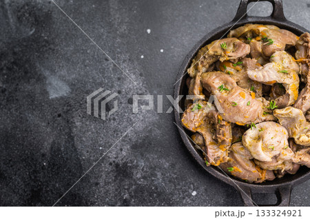 Cooked stew from poultry gizzards with herbs in cast iron pan on dark stone background perfect for rustic food photography and menu design. 133324921
