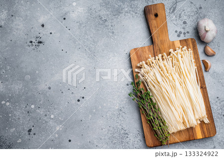 Cooking preparation flat lay Enoki fungi, fresh thyme, and garlic on a rustic board and modern concrete surface. 133324922