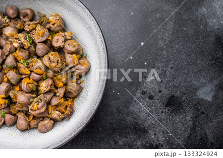 Tasty giblets stew served in gray plate on textured black surface ideal for culinary blogs or traditional meal visuals. Tasty giblets stew served in gray plate on textured black surface ideal for culinary blogs or traditional meal visuals. 133324924