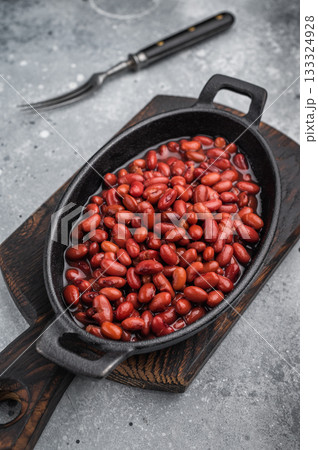 Kidney beans in a cast iron skillet on a rustic wooden board. Large gray copy space for text. Overhead, minimal style. 133324928