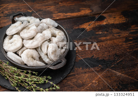 Heap of icy frozen seafood (shrimp prawns) on a wooden table, perfect for dinner, lunch, or appetizer recipes. 133324951