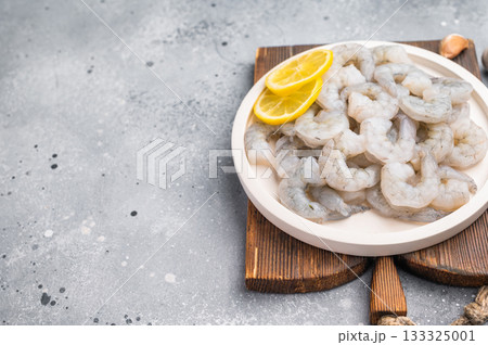 Fresh prawn shrimp tails on a wooden board. Gourmet ingredient with spices and lemon slices, ready for cooking on a rustic table. Fresh prawn shrimp tails on a wooden board. Gourmet ingredient with spices and lemon slices, ready for cooking on a rustic table. 133325001