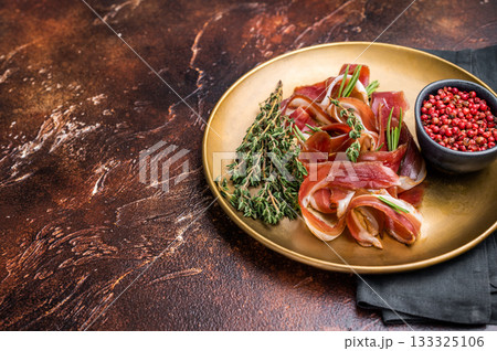 Cured duck fillet meat slices, magret smoked poultry on a plate. brown background. top view Cured duck fillet meat slices, magret smoked poultry on a plate. brown background. top view 133325106