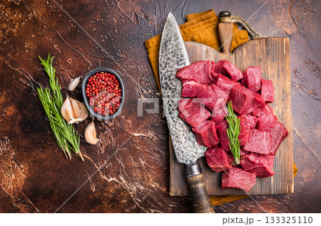 Diced Raw Venison meat, fresh Wild Roe Deer Game Meat on butcher cutting board. brown background. top view 133325110