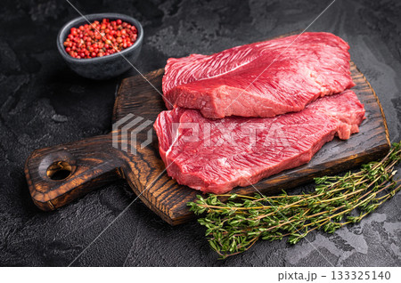Raw Boar meat steak, uncooked Game Meat on cutting board. black background. top view Raw Boar meat steak, uncooked Game Meat on cutting board. black background. top view 133325140